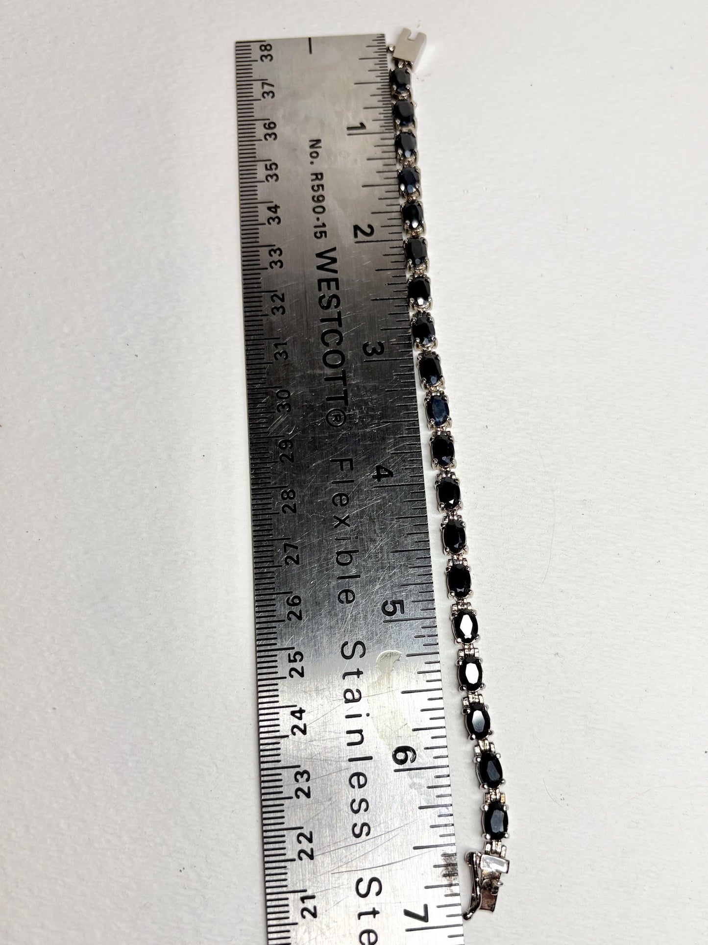 A 7-inch stainless steel tennis bracelet with oval dark blue sapphires.