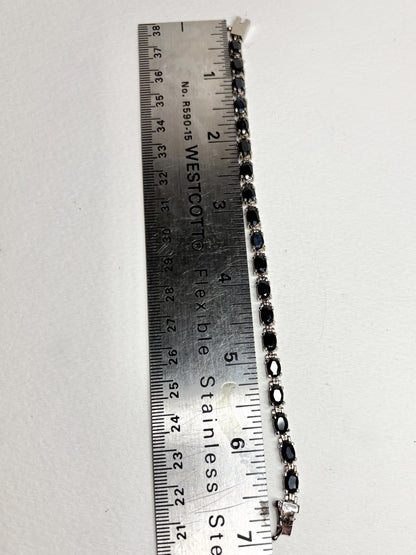 A 7-inch stainless steel tennis bracelet with oval dark blue sapphires.