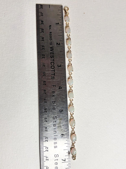 Gold plated tennis bracelet with 11 oval opals, measured against a ruler.