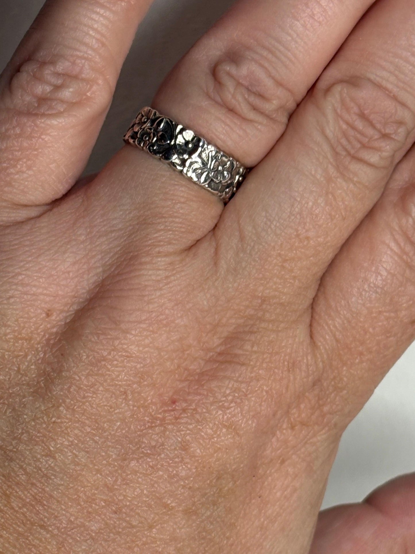 Sterling silver eternity band ring with a forget-me-not floral pattern.