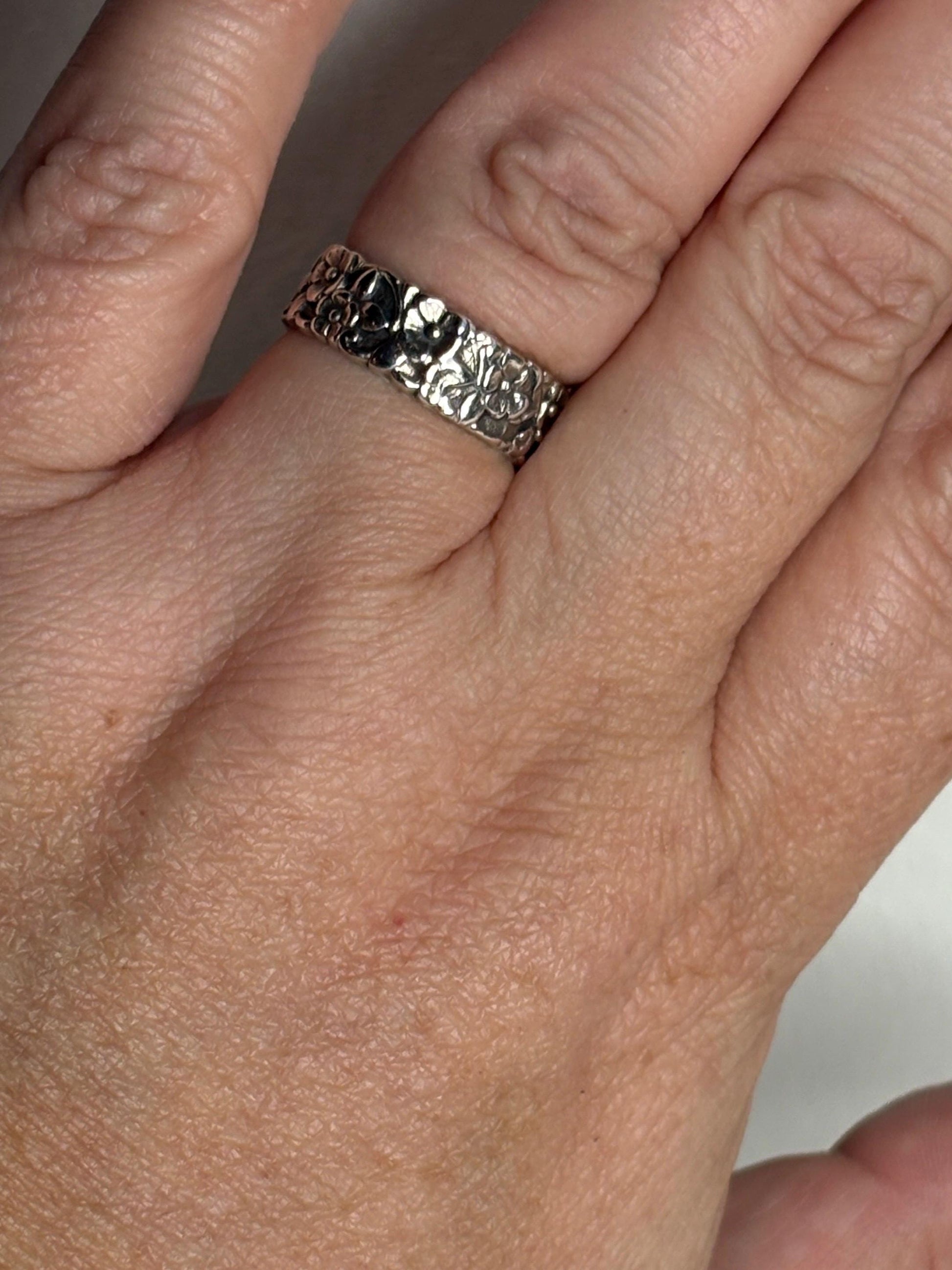 Sterling silver eternity band ring with a forget-me-not floral pattern.