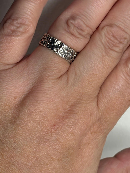 Sterling silver eternity band ring with a forget-me-not floral pattern.