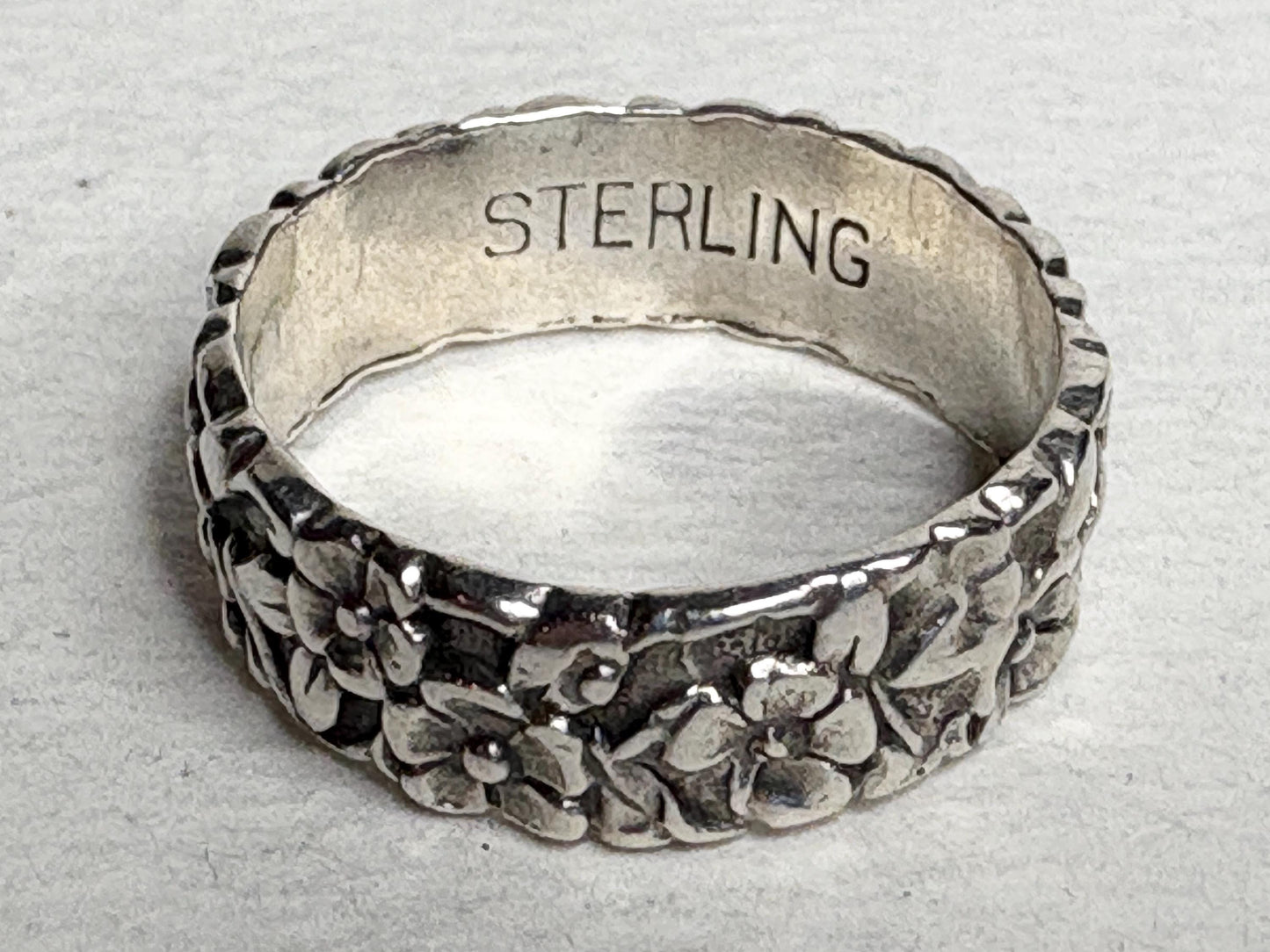 Sterling silver eternity band ring with forget-me-not floral design.
