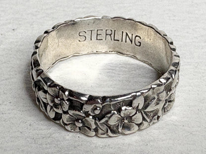 Sterling silver eternity band ring with forget-me-not floral design.