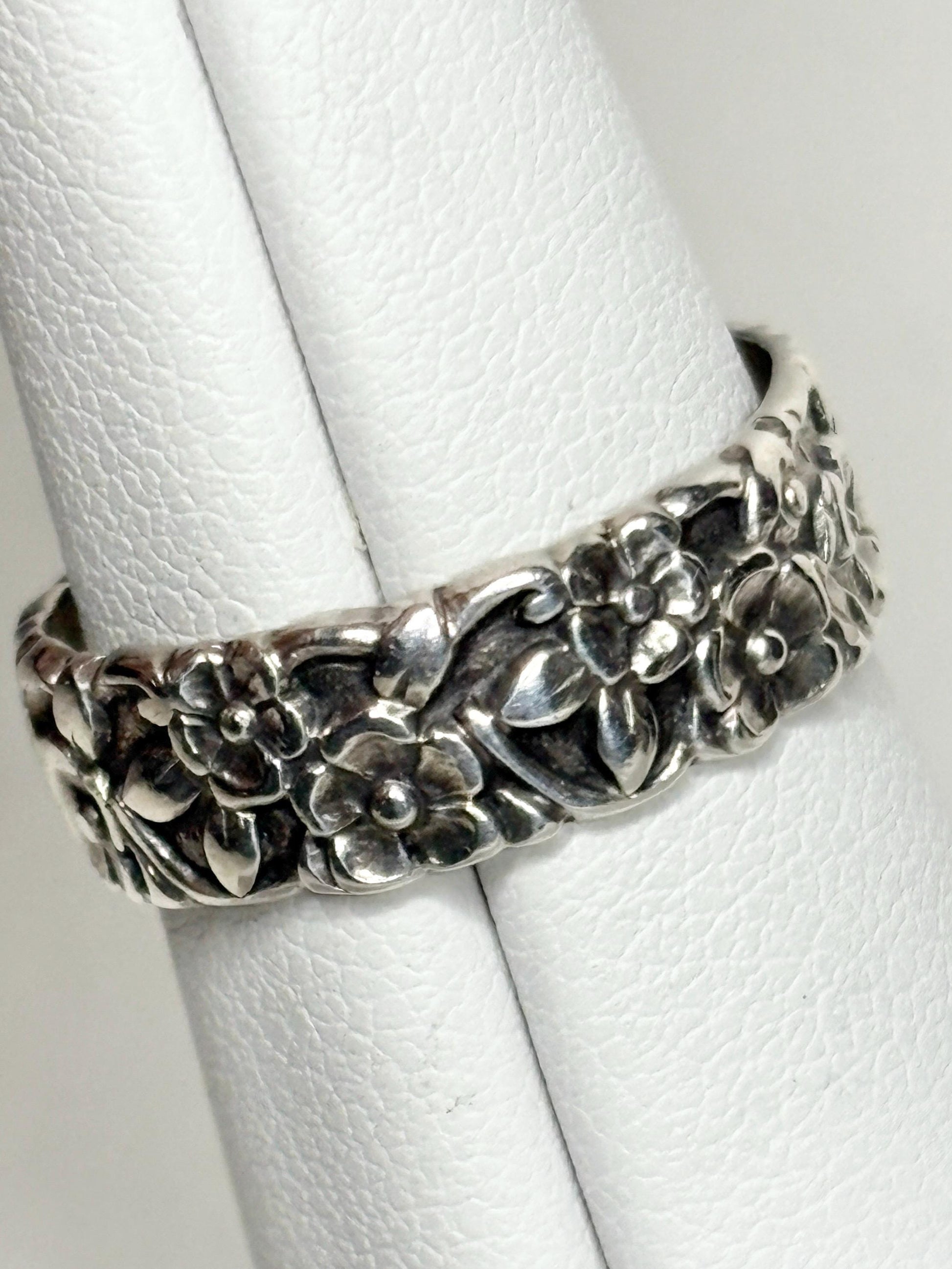 Sterling silver eternity band ring with forget-me-not floral design.