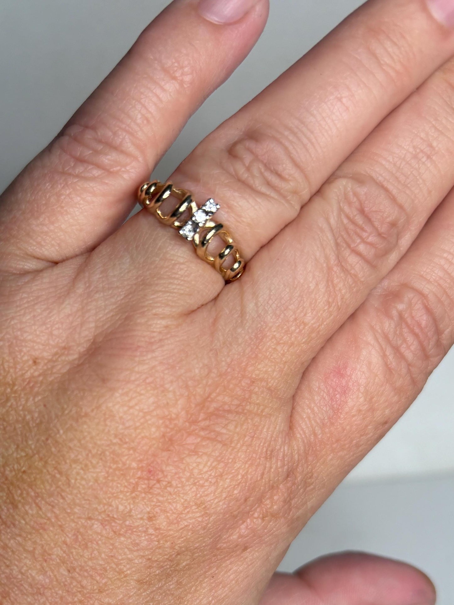 Vintage 14k gold ring with three diamonds and a ribbon loop design.