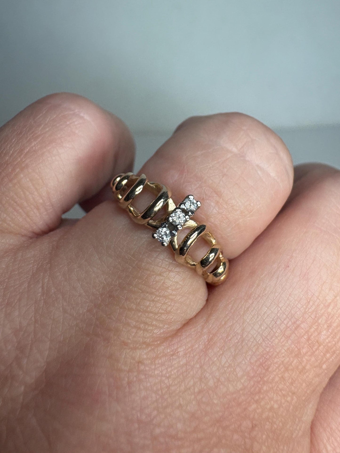 A vintage 14k gold ribbon loop ring with three small diamonds.