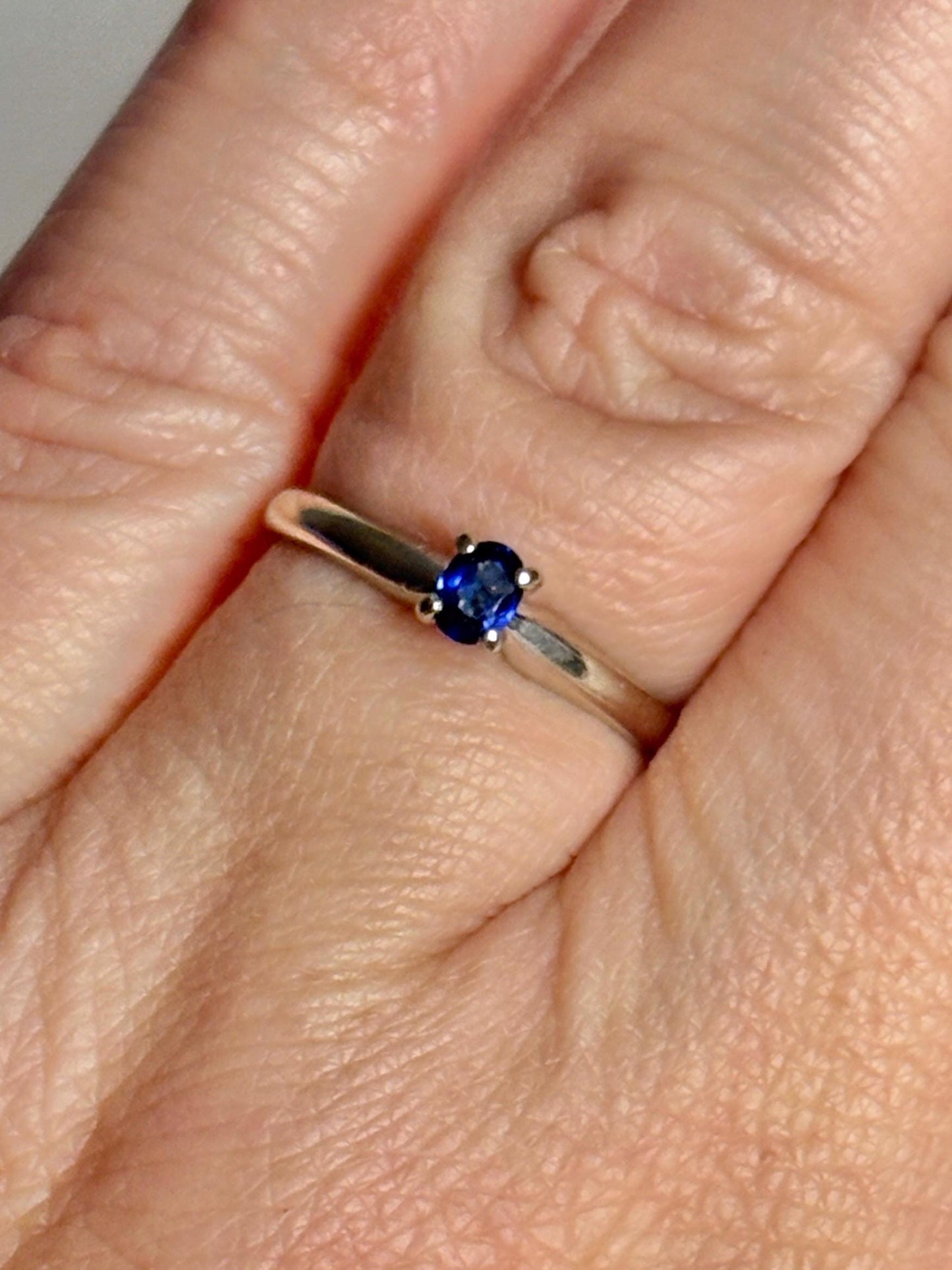 A vivid violetish blue oval sapphire solitaire in a 14k white gold ring.