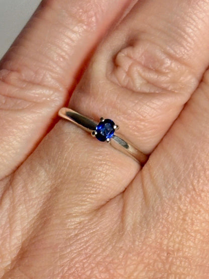A vivid violetish blue oval sapphire solitaire in a 14k white gold ring.