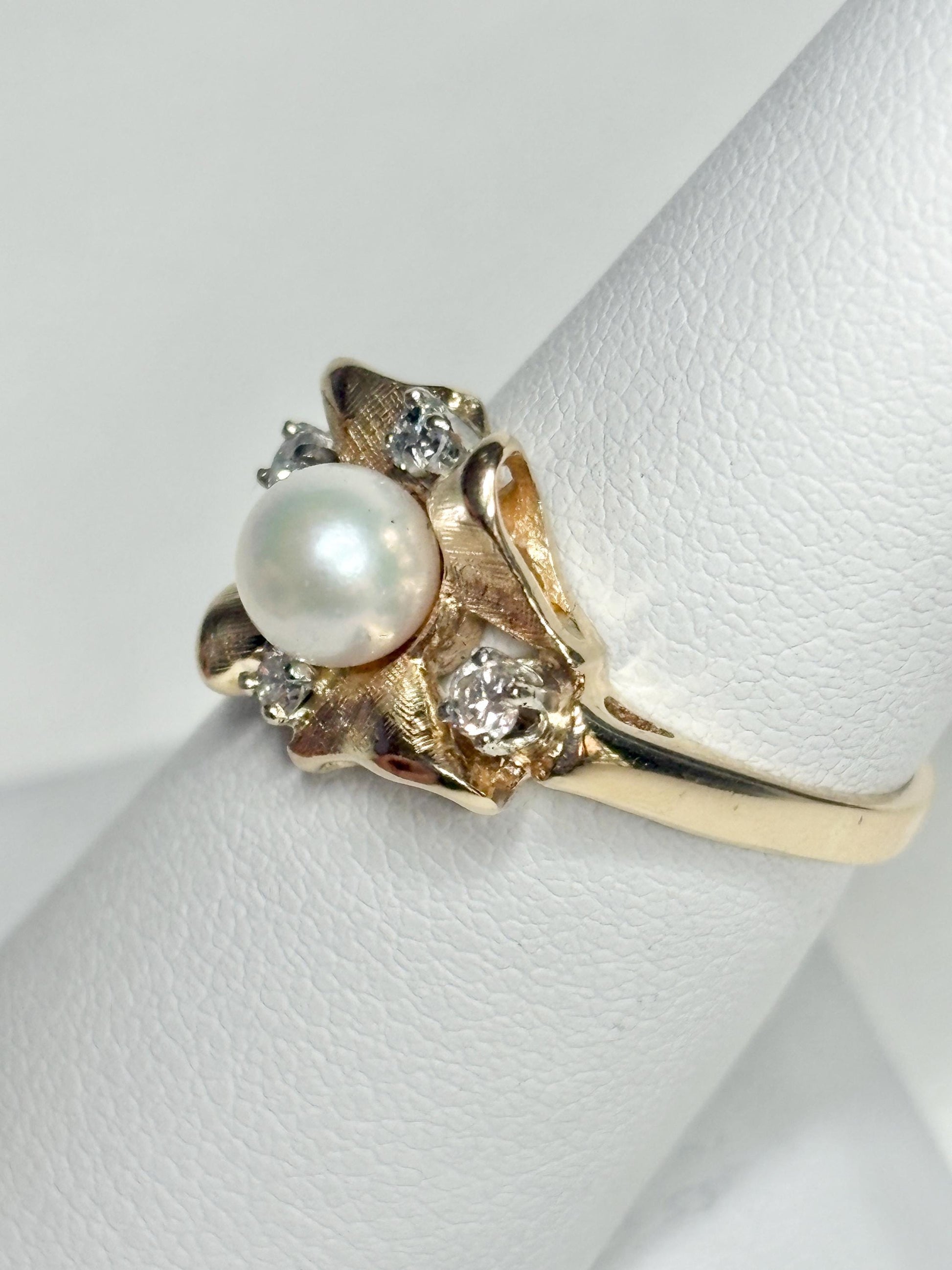 A 14k gold ring featuring a pearl and diamonds in a bow design.