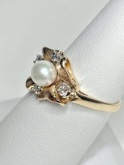 A 14k gold ring featuring a pearl and diamonds in a bow design.