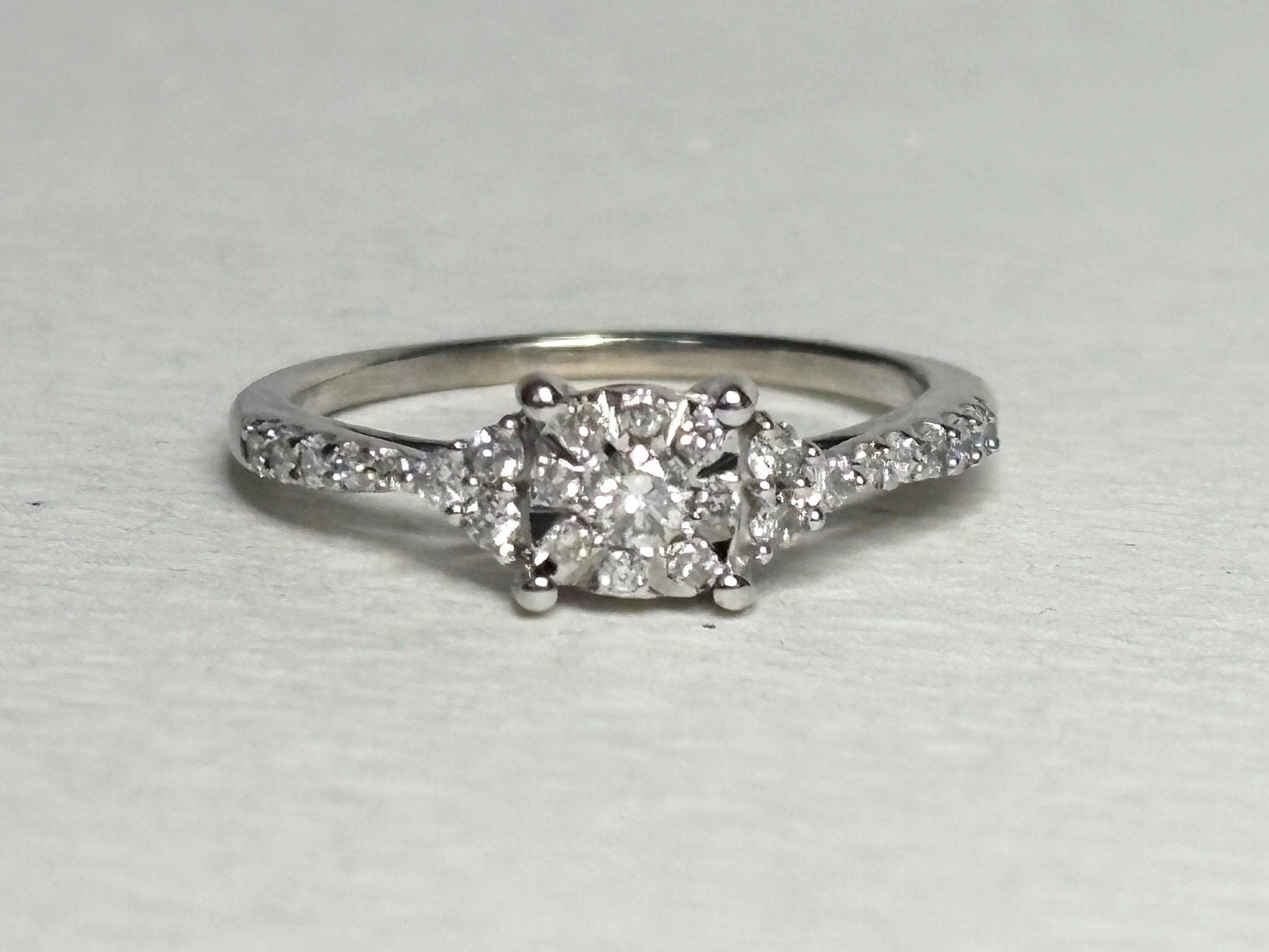 A 14k white gold ring with a squared diamond cluster center and diamond accents.