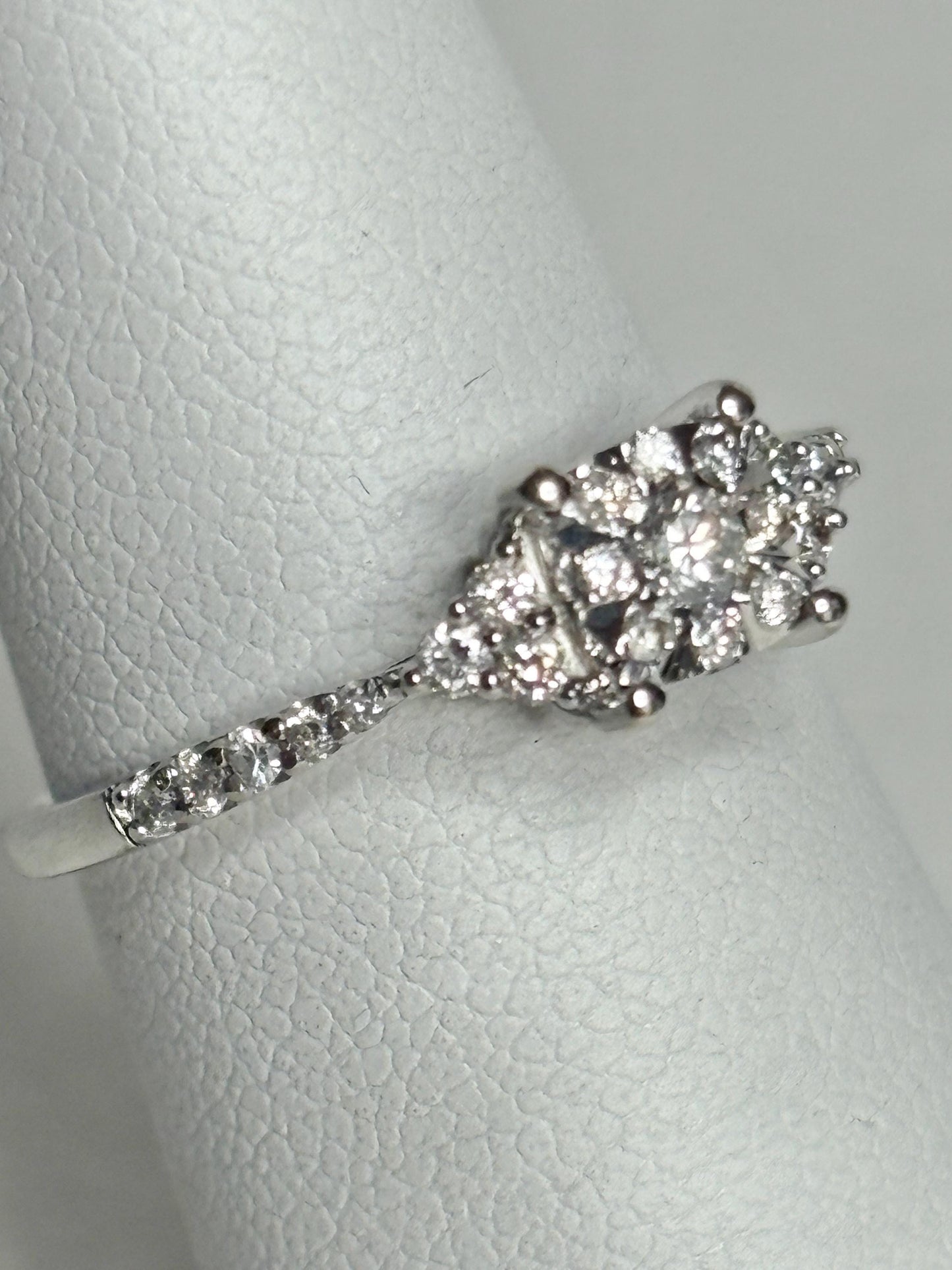 A 14k white gold ring with a cluster of diamonds on a band of diamonds.