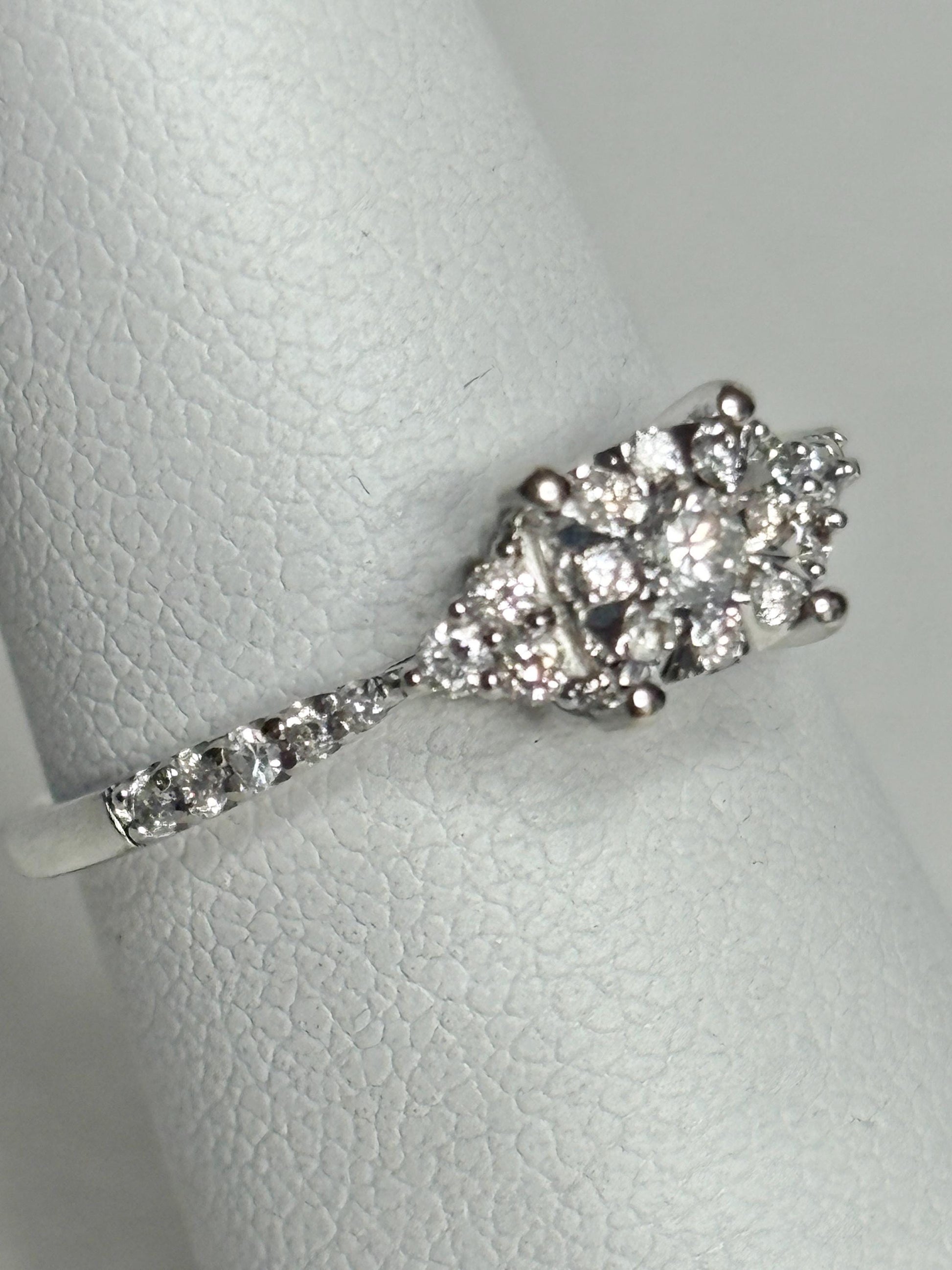 A 14k white gold ring with a cluster of diamonds on a band of diamonds.