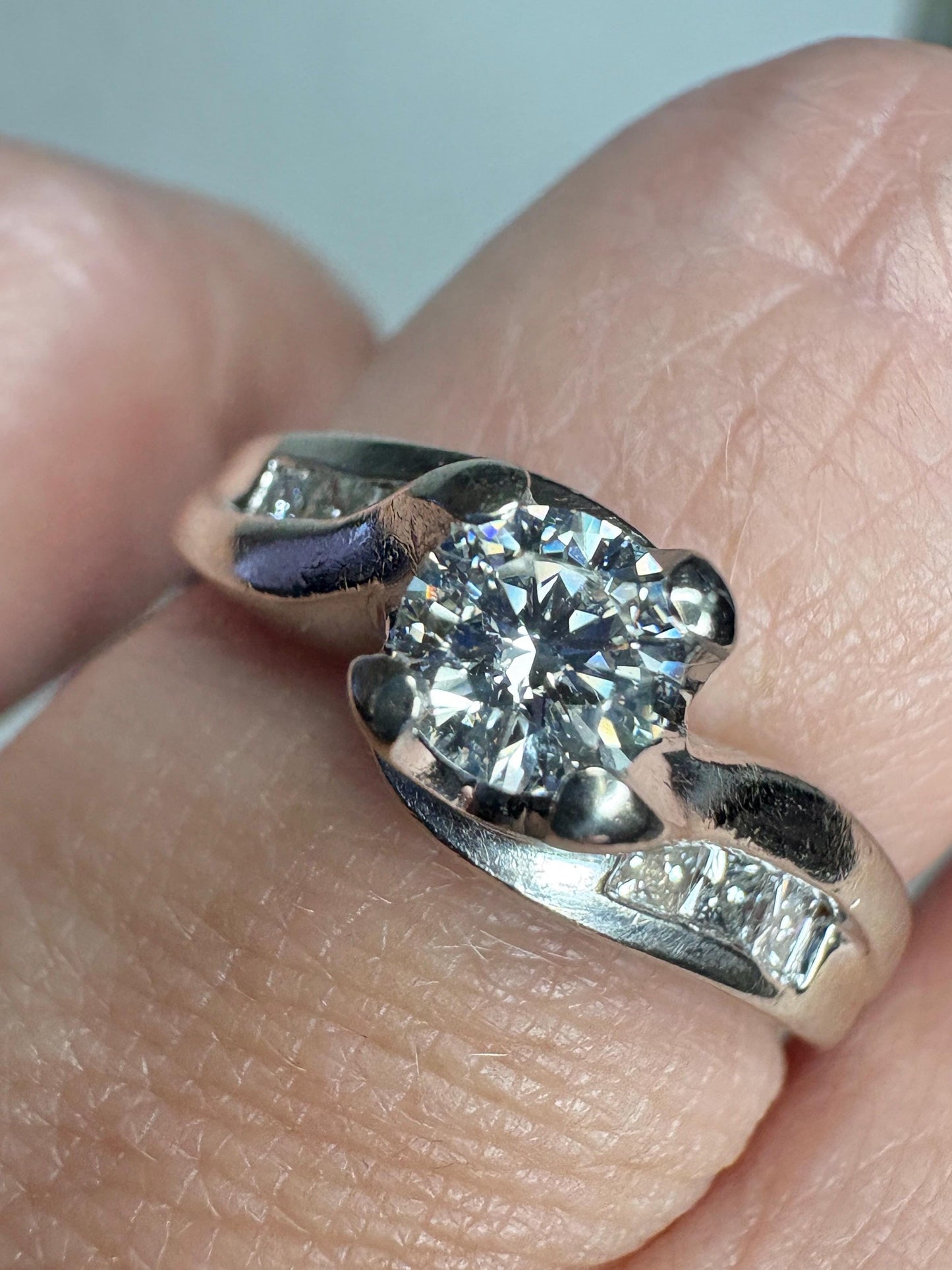 A vintage 14k white gold engagement ring with a central diamond and channel-set princess-cut diamonds.