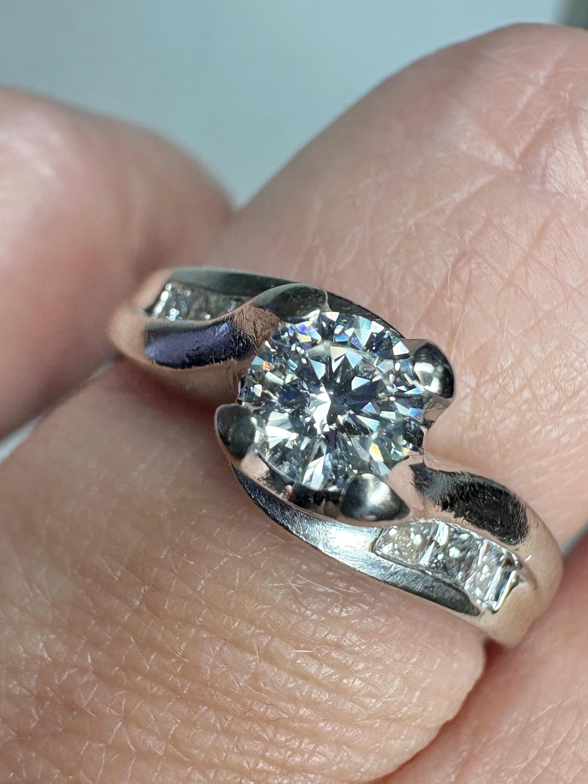 A vintage 14k white gold engagement ring with a central diamond and channel-set princess-cut diamonds.