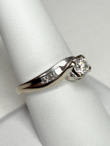 A vintage 14k white gold ring with a central diamond and channel-set princess cut diamonds.
