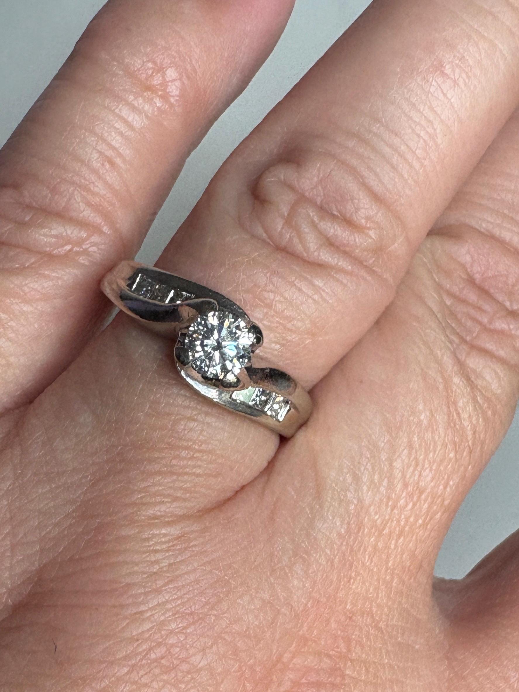 A vintage 14k white gold ring with a central diamond and channel-set princess cut diamonds.