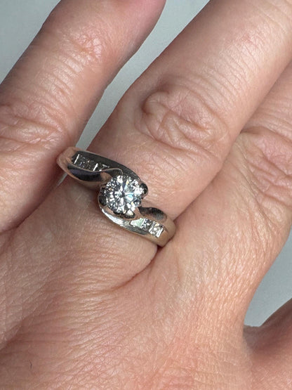 A vintage 14k white gold ring with a central diamond and channel-set princess cut diamonds.