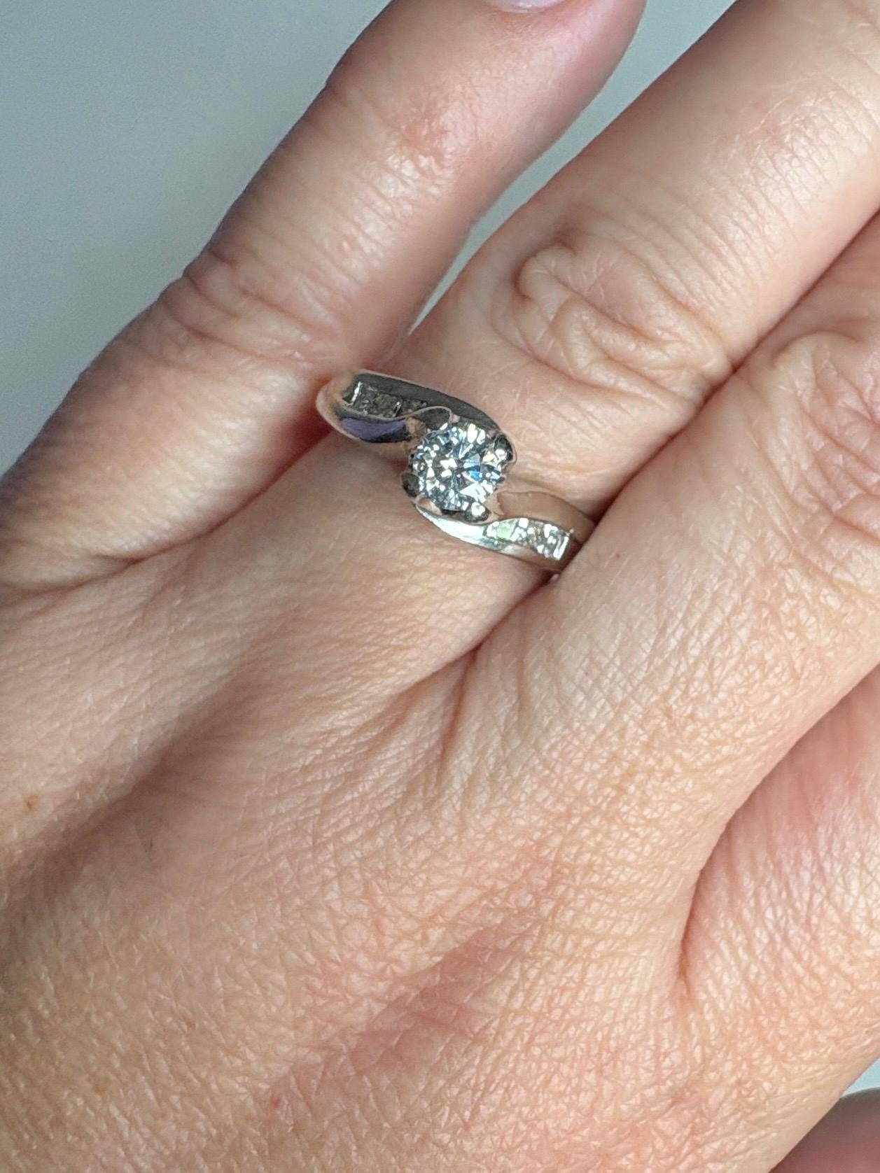 A vintage 14k white gold ring with a central diamond and channel-set princess cut diamonds.