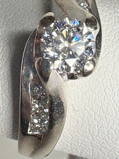 A vintage 14k white gold engagement ring with a central diamond and channel-set princess cut diamonds.