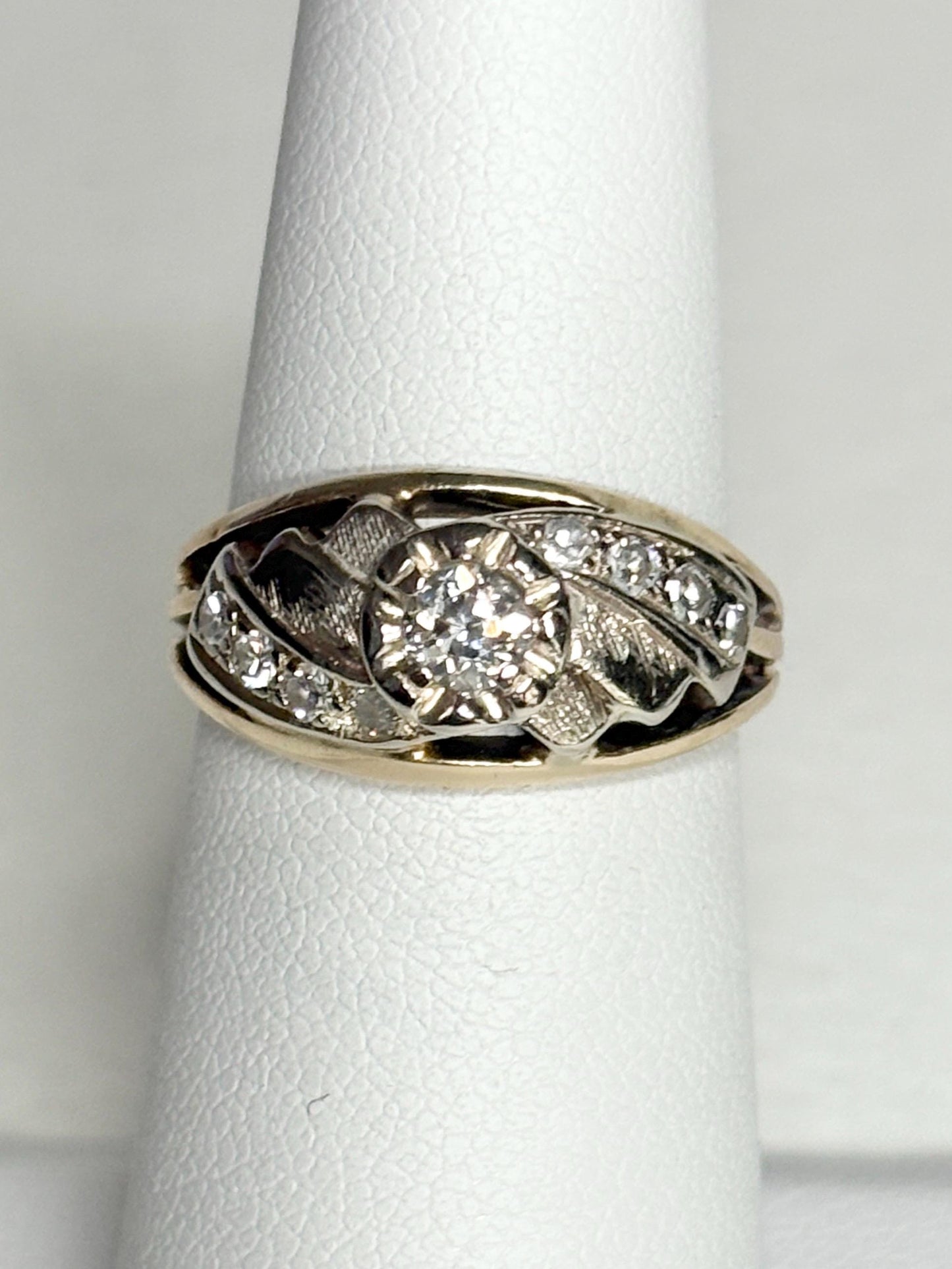 Mid-century two-tone 14k gold ring with a central diamond and smaller side diamonds.