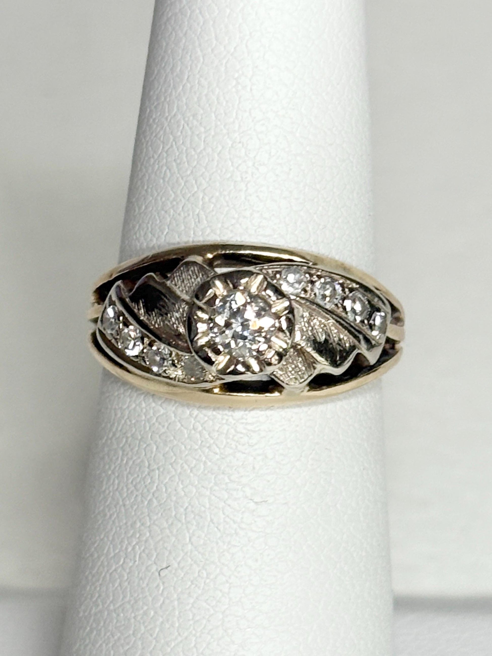 Mid-century two-tone 14k gold ring with a central diamond and smaller side diamonds.