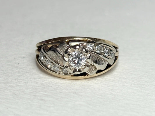 Mid-century two-tone 14k gold ring with a central diamond and smaller side diamonds.