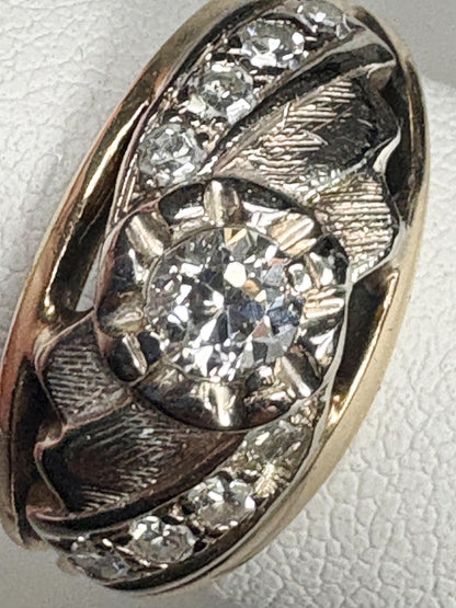 Mid-century two-tone 14k gold ring with a central diamond and smaller side diamonds.