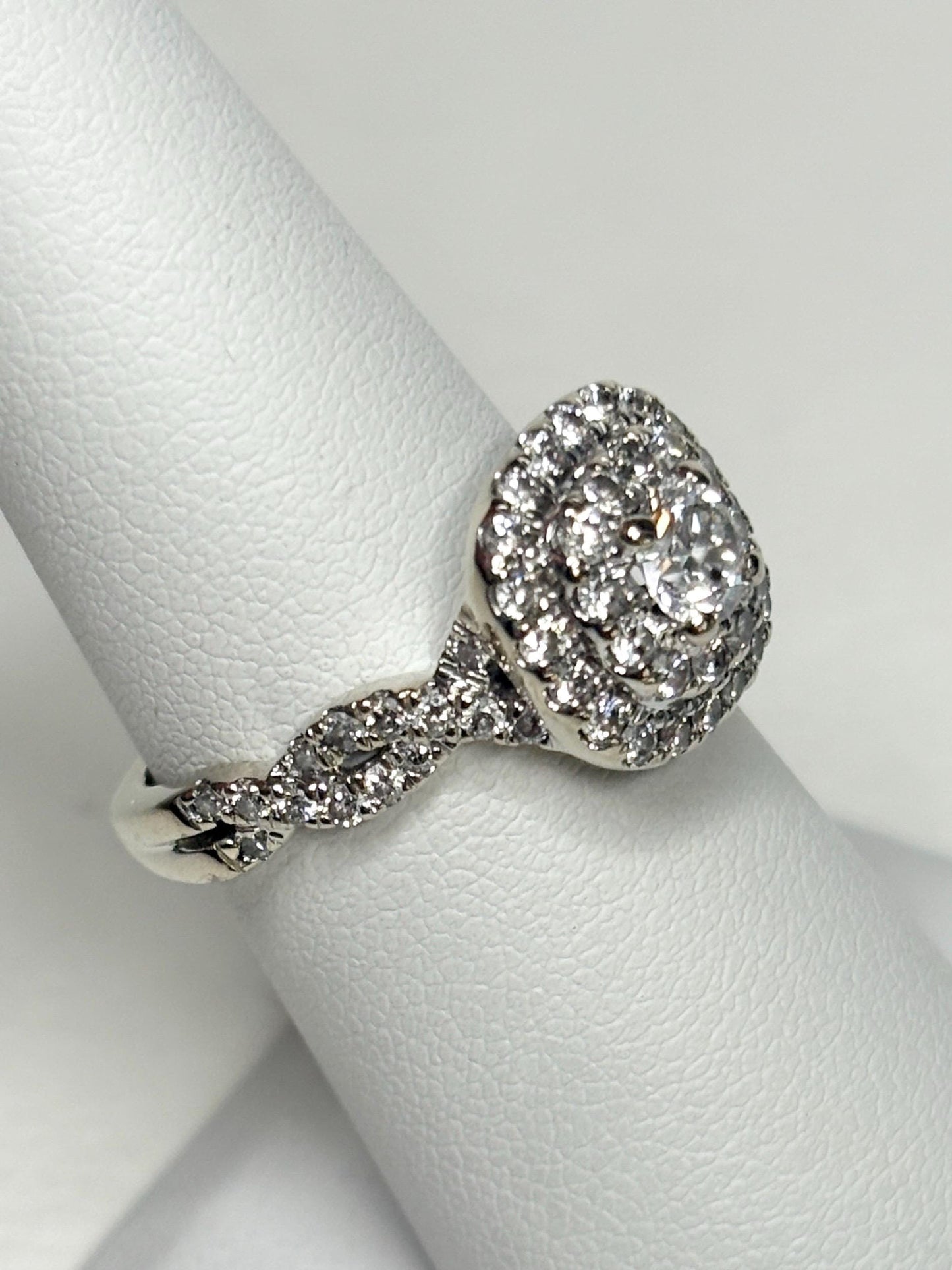 A 14k white gold ring with a central diamond surrounded by a double halo of smaller diamonds.