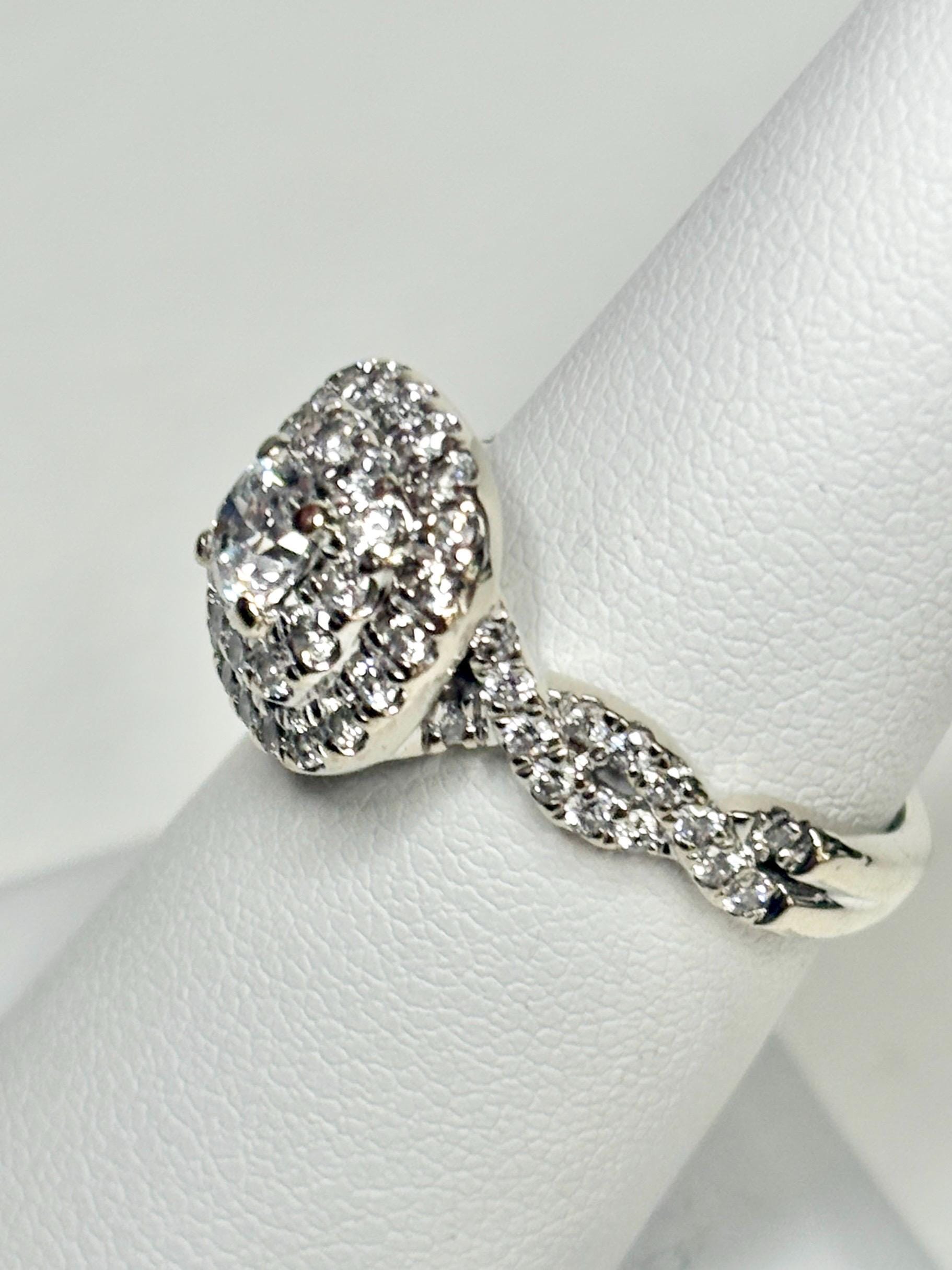 A 14k white gold ring with a central diamond and a double halo of smaller diamonds.