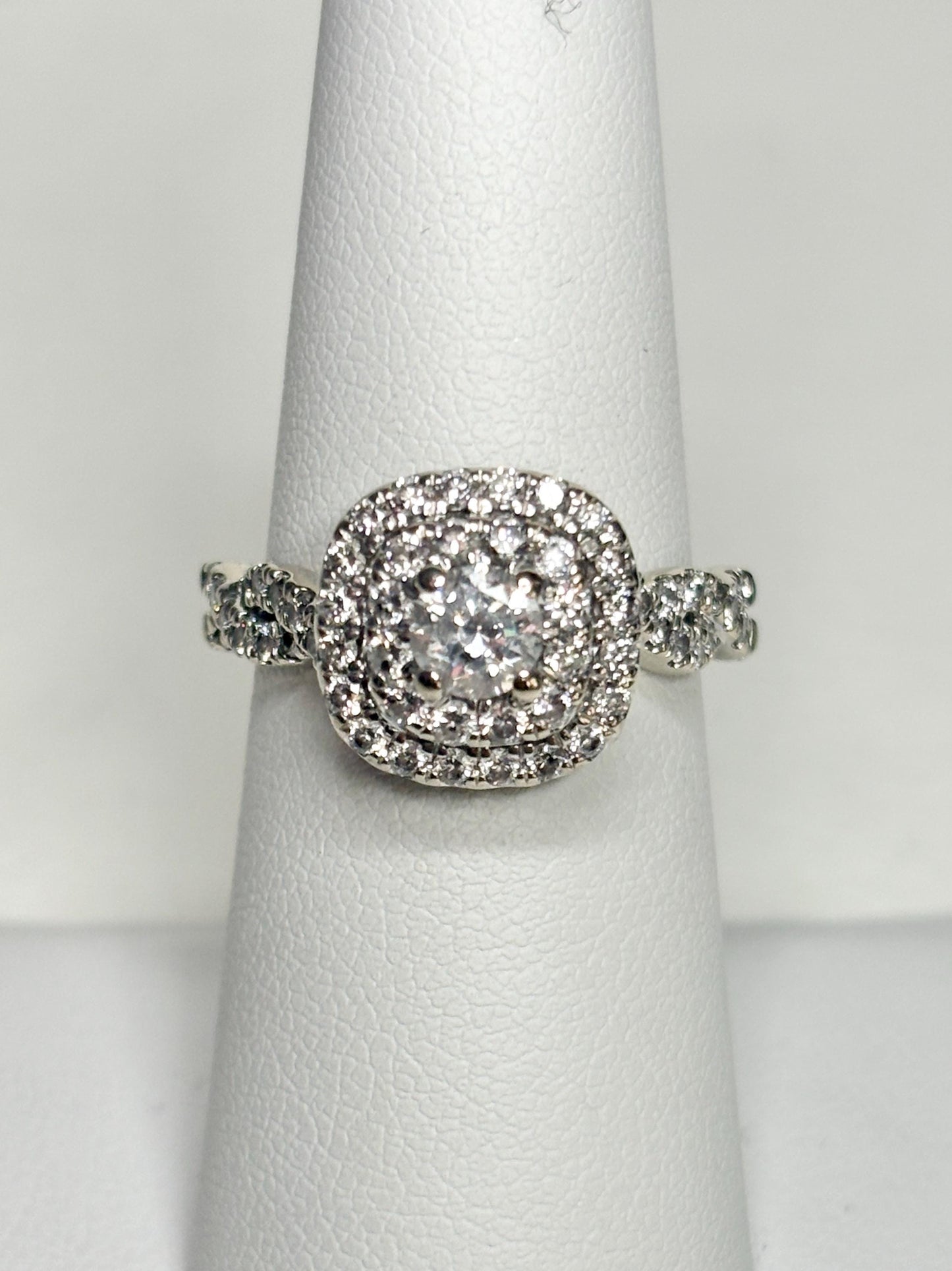A 14k white gold ring with a central diamond surrounded by a double halo of smaller diamonds.