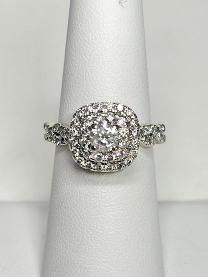 A 14k white gold ring with a central diamond surrounded by a double halo of smaller diamonds.