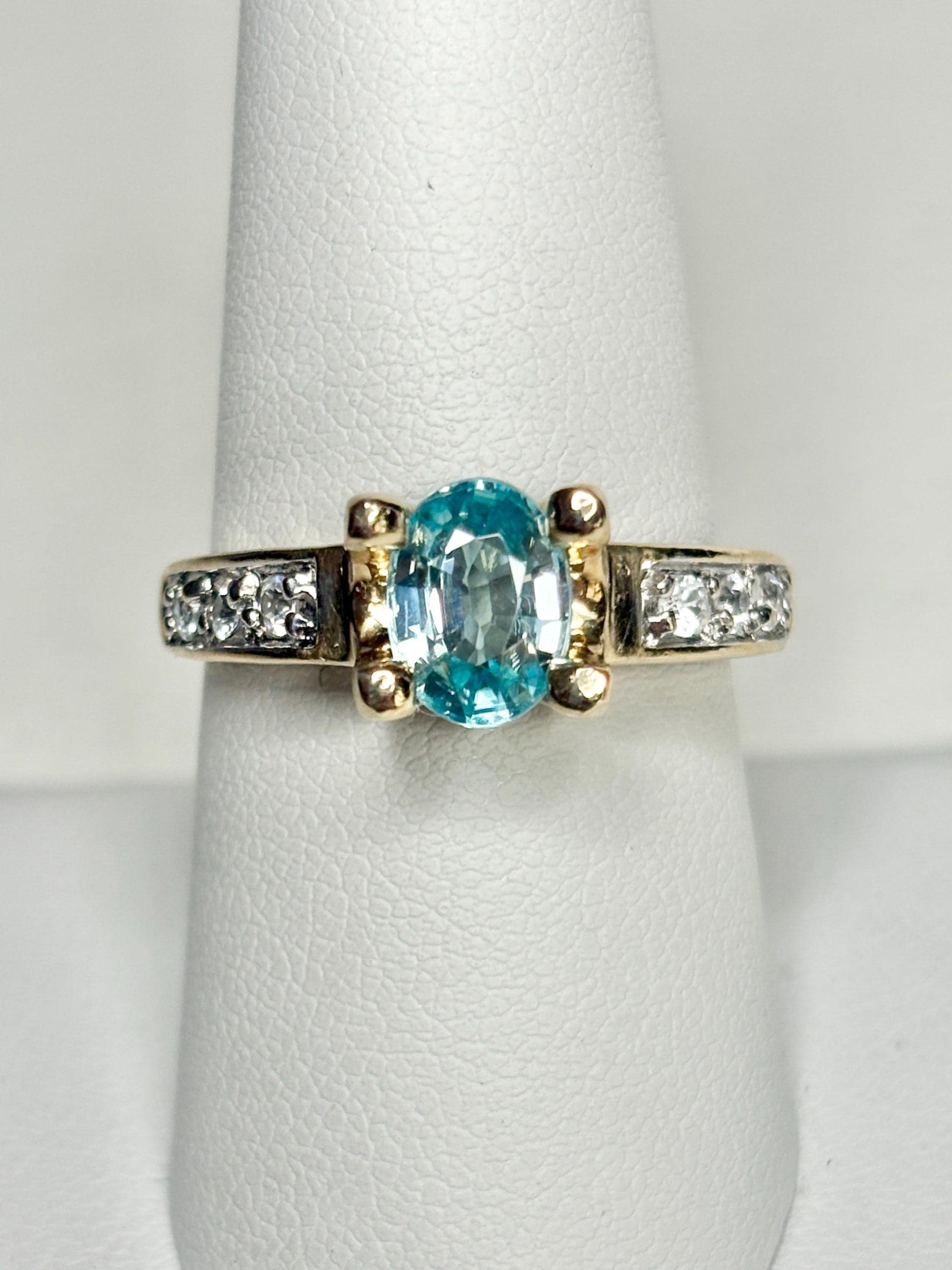 Oval blue zircon and clear side stones in a two-tone 14k gold ring.