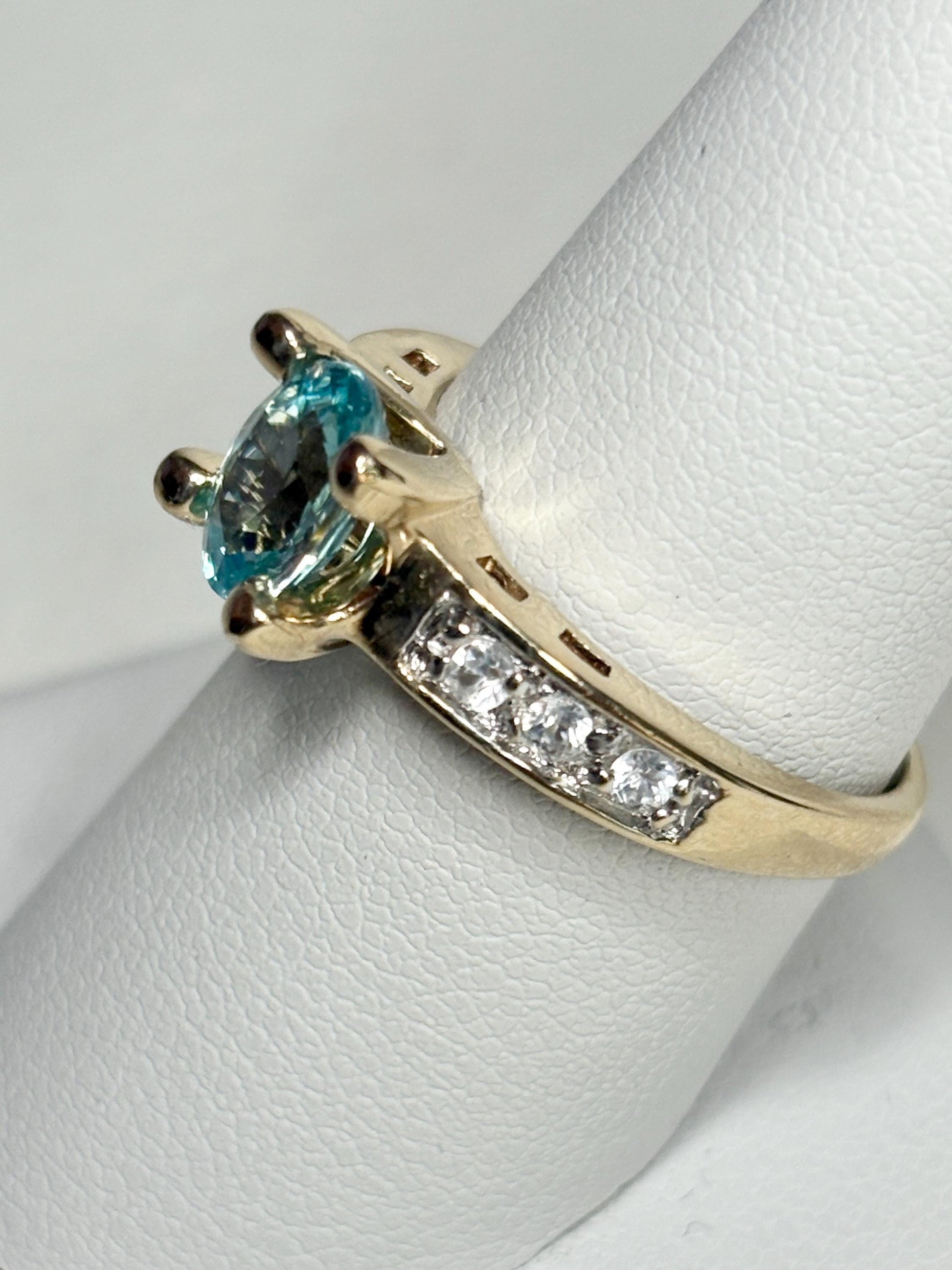 A 14k gold ring with a blue oval zircon and clear side stones.