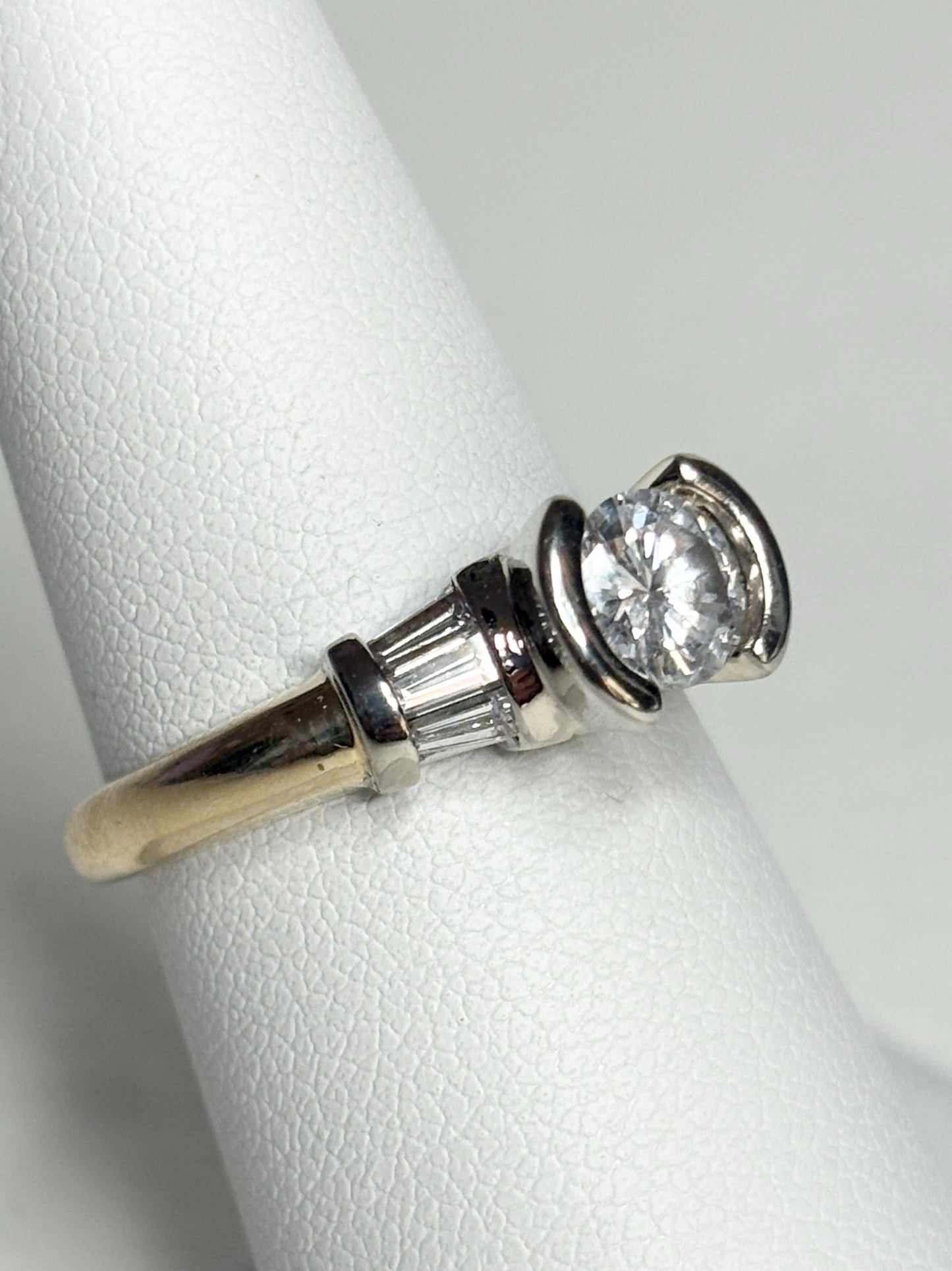 A 14k two-tone gold ring with a round diamond and baguette accents.