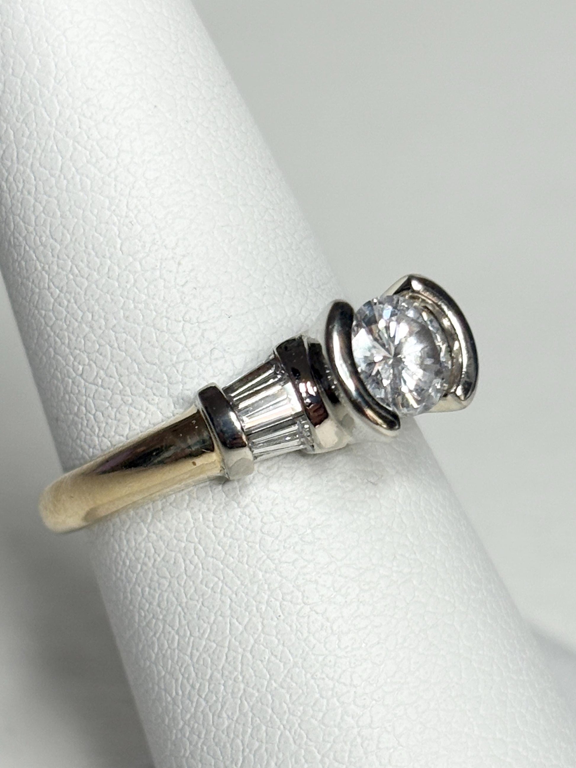 A 14k two-tone gold ring with a round diamond and baguette accents.