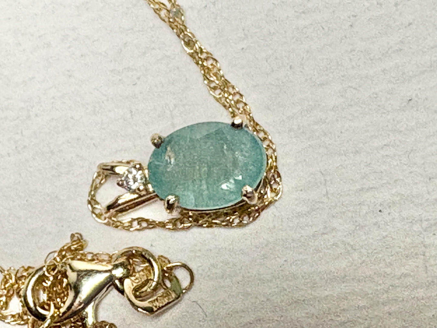 14k gold necklace with an oval grandidierite and diamond solitaire pendant.