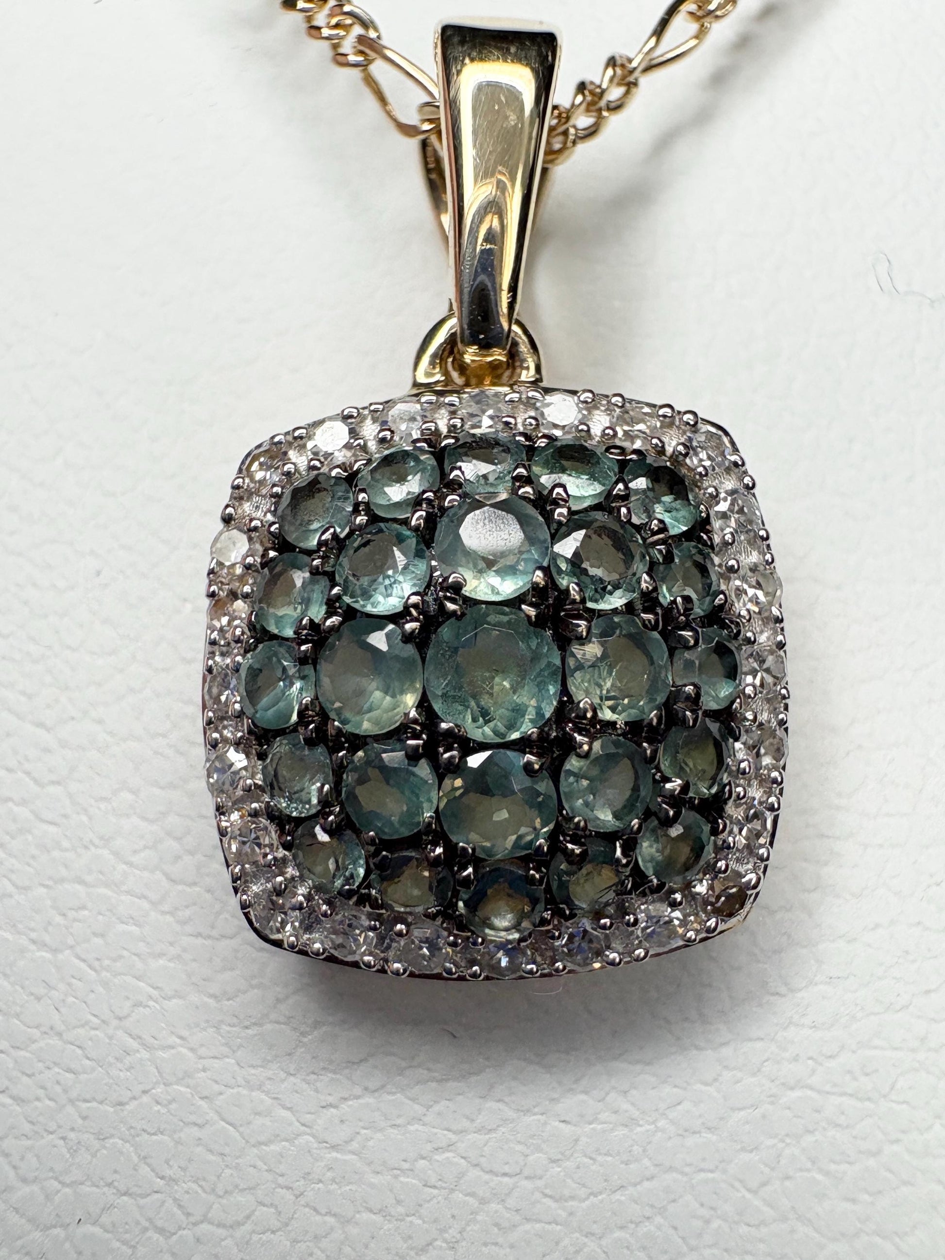 A 14k gold pendant with alexandrite and diamond cushion cluster on a figaro chain.