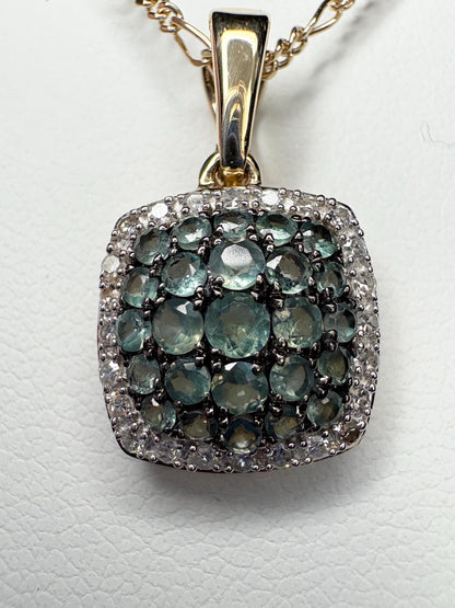 A 14k gold pendant with alexandrite and diamond cushion cluster on a figaro chain.