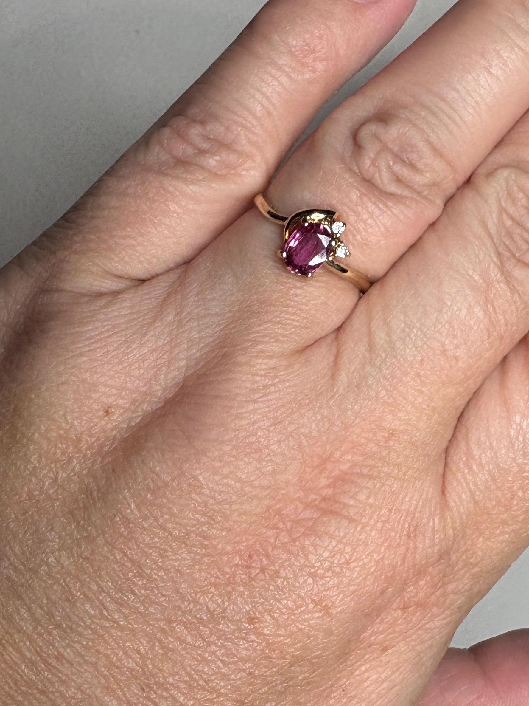 A dainty 14k gold ring with a pink sapphire and two small diamonds.