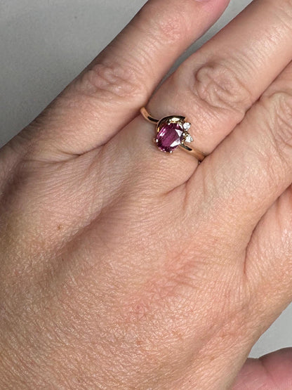 A dainty 14k gold ring with a pink sapphire and two small diamonds.