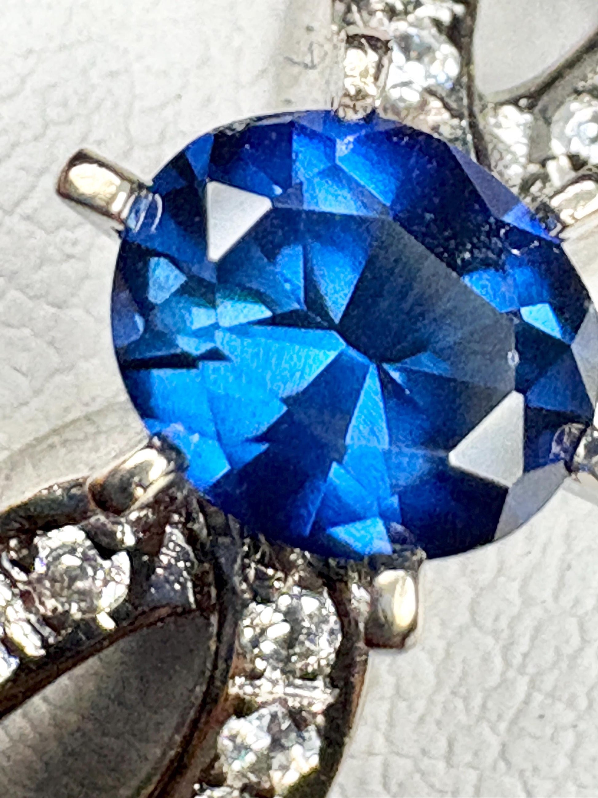 A vivid blue sapphire oval ring with diamonds in 18k white gold.