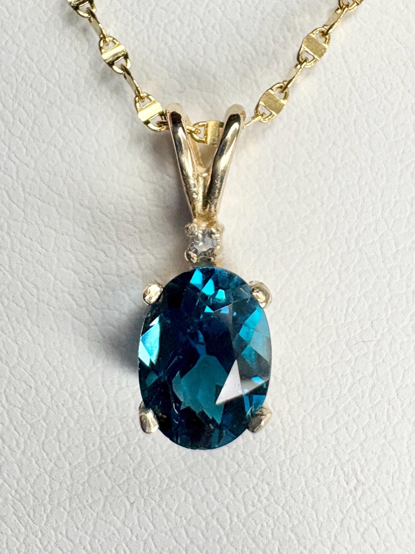 Oval London blue topaz pendant necklace with diamond accent on 14k gold chain.