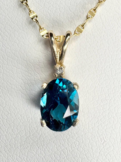 Oval London blue topaz pendant necklace with diamond accent on 14k gold chain.