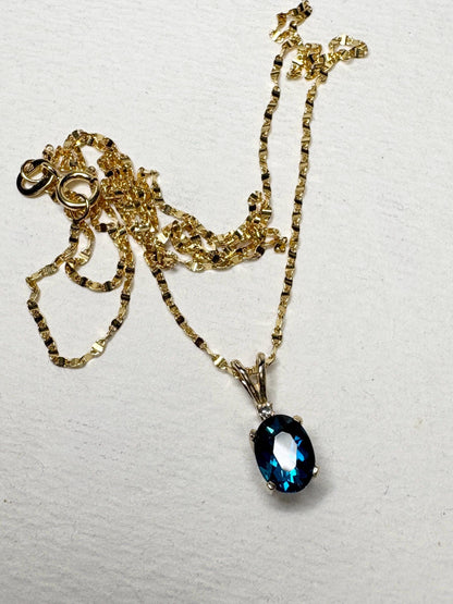 14k gold necklace with a vibrant oval London blue topaz and diamond accent pendant.