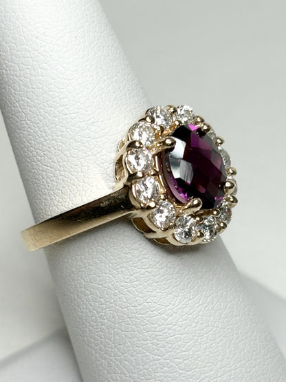 A 14k yellow gold ring featuring a checkerboard faceted rhodolite garnet surrounded by diamonds.