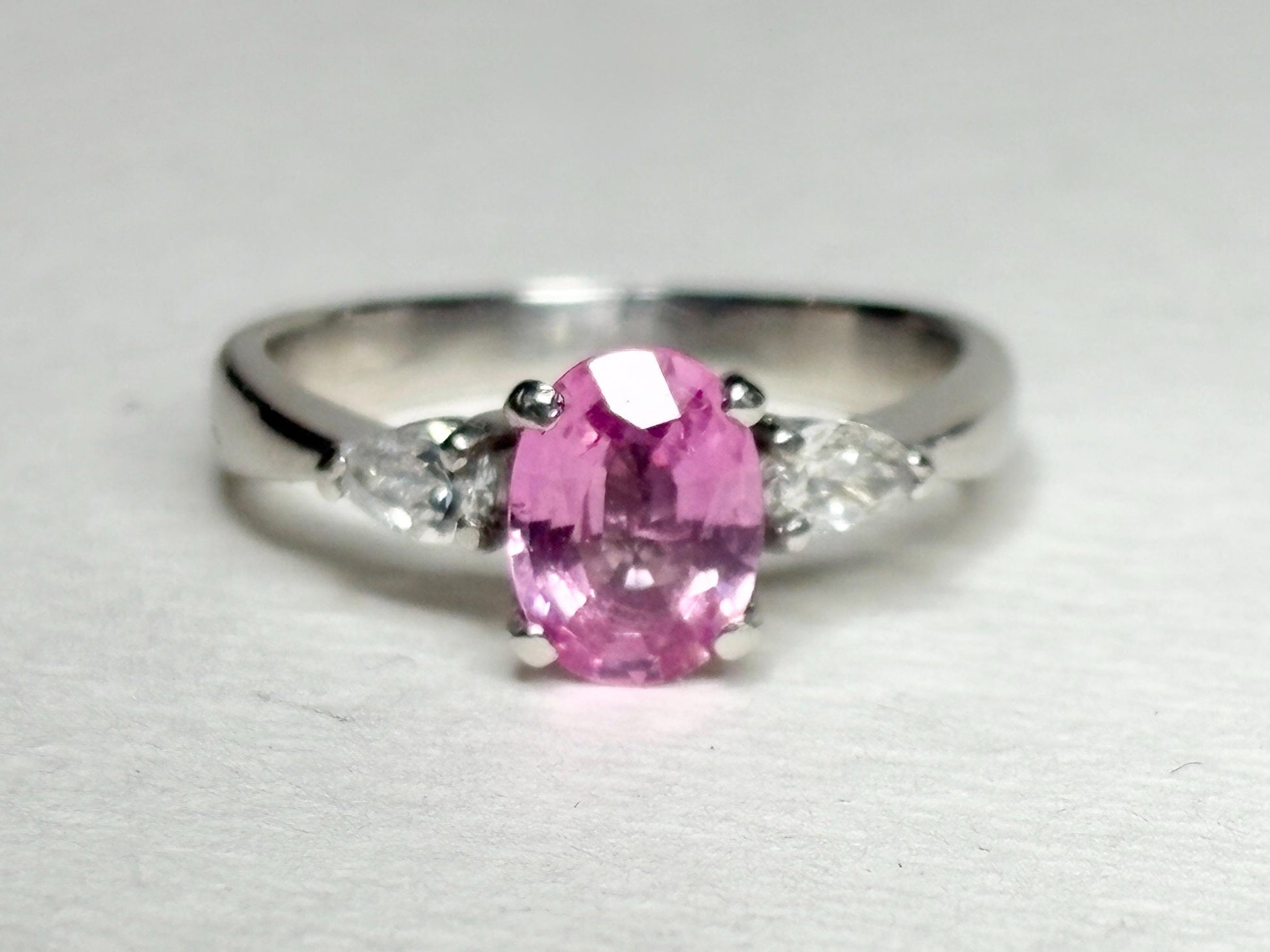 Platinum ring with oval pink sapphire and pear diamonds.