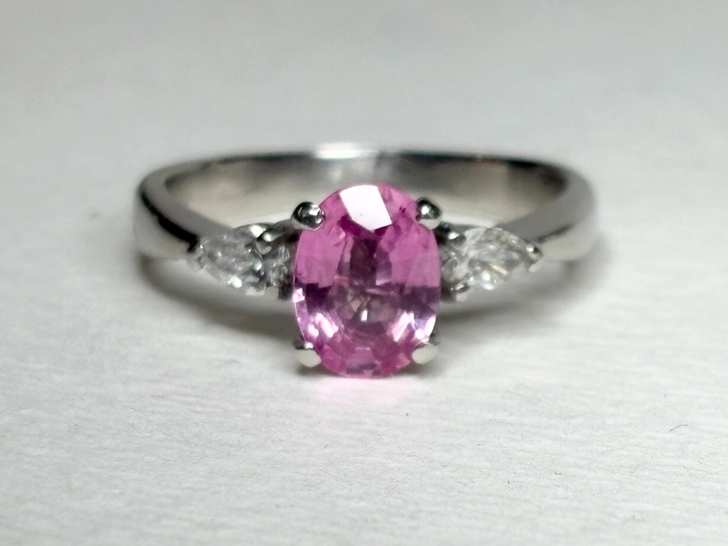 Platinum ring with oval pink sapphire and pear diamonds.