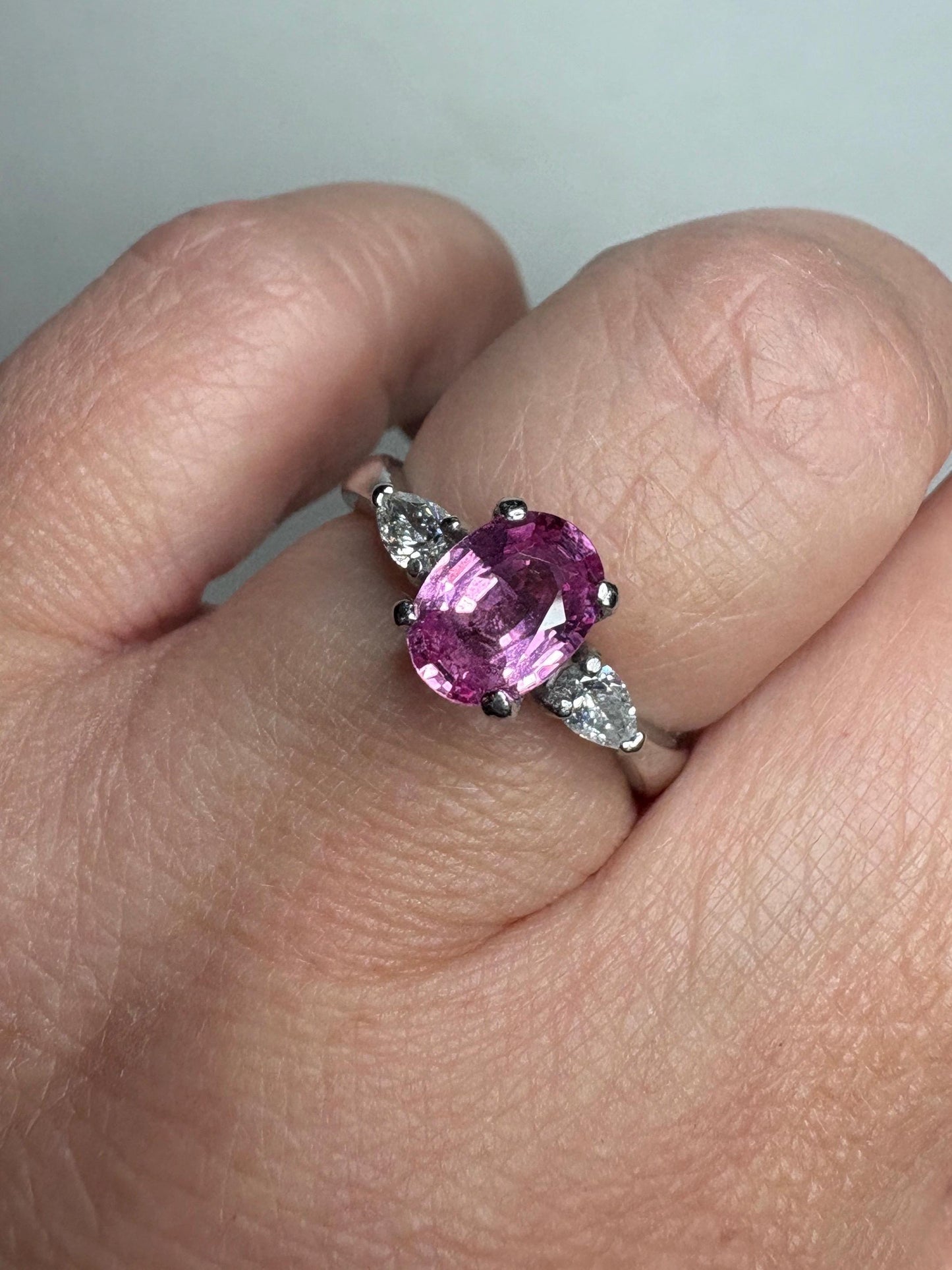 Platinum ring with oval pink sapphire and two pear diamonds.